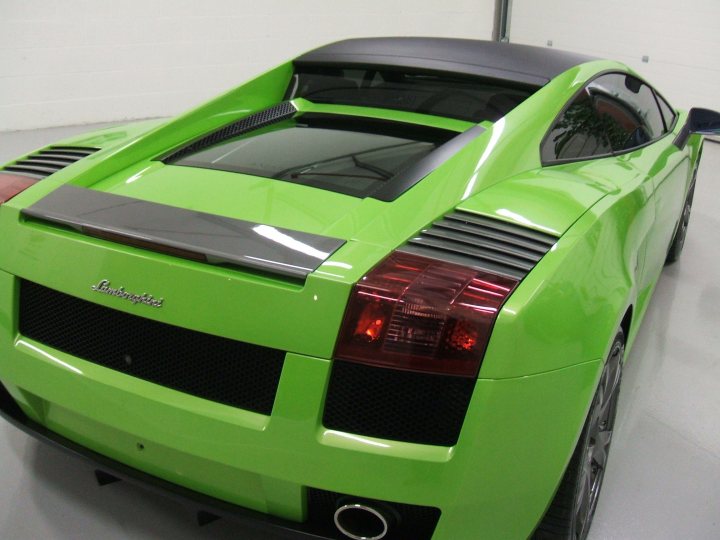 my detailed mistress pics - VI gallardo - Page 1 - Gallardo/Huracan - PistonHeads - The image features an eye-catching green Lamborghini car, prominently displayed in a spacious warehouse or garage with white walls. The car is viewed from the rear side of the vehicle, showcasing its distinctive rear spoiler, glossy bodywork reflecting the indoors environment, the bold and iconic Lamborghini logo on the right side of the rear panel, and the dual chrome exhaust tips on the right side of the rear wing. The car's stance and design suggest speed and performance, embodying the luxury and sportiness associated with high-end sports cars.