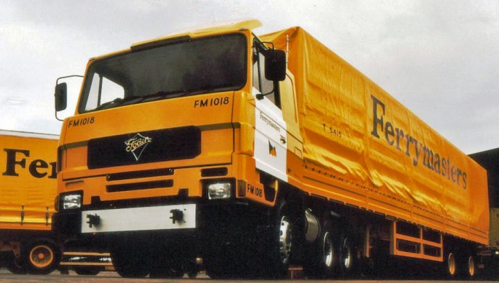 "Super single" tyres - pros and cons? - Page 1 - Commercial Break - PistonHeads - This image shows a sturdy, yellow ferrymasters truck parked on a road with its cargo compartment bearing the name of the company. The side of the truck features a bold black stripe, and the back of the cab indicates "FMI 108". The lorry, also emblazoned with "FERRYMASTERS", seems to be stationed near another vehicle, their details less clear. The scene conveys a business or work-related environment.