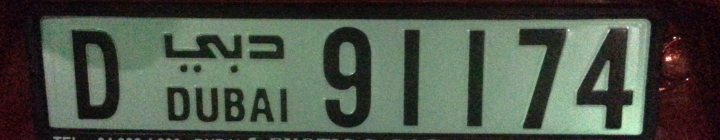 A close up of a street sign with a sky background - Pistonheads - The image shows a close-up view of a license plate on a vehicle. The license plate has a mix of characters, including Arabic numerals and letters. It's predominantly green with white text and numbers. The plate also includes a combination of black and white Arabic numerals and letters, which suggests that this could be from a region where Arabic script is used. The first part of the license plate reads "D," and the rest is partially obscured, but it reads "Dubai" near the end of the plate.