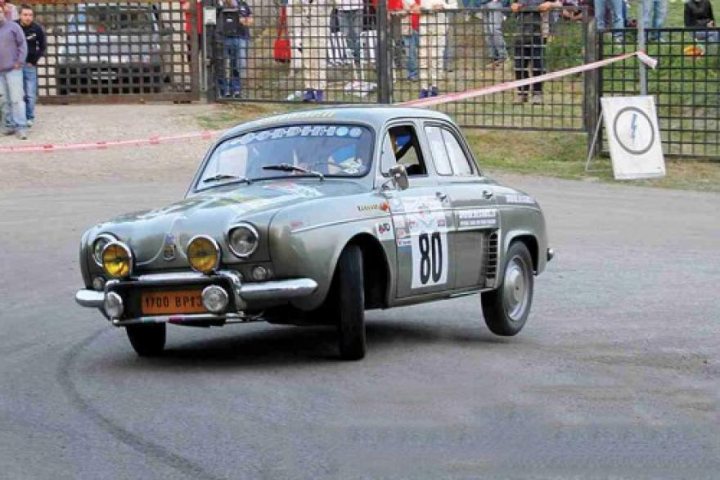 Renault Gordini Dauphine 610 1960 Newbie - Page 1 - French Bred - PistonHeads - The image showcases a silver Volkswagen car, possibly stationary or driving with its headlights on, and the number 80 painted on its side. The car is situated on what seems to be a racetrack or a public road with racing rules indicated by the presence of a number "5" flag. The backdrop is a crowd of spectators, suggesting that this might be a race or auto event. The atmosphere suggests excitement and anticipation.