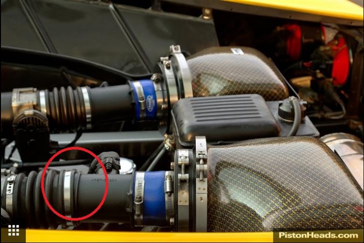 Giallo 360 Modena @ tfc with hamann + upgrades - Page 1 - Ferrari V8 - PistonHeads - The image is a close-up photograph focused on a mechanical component, specifically what appears to be the engine of a vehicle. It features a series of pipes or tubes with a mix of parts that suggest the mechanical workings of the engine, with some components highlighted by a red circle. The components are seen from an above perspective, allowing a detailed view of the metallic structures and craftsmanship typical in automotive engine designs. The style of the image is realistic and emphasizes the complexity and intricacies of the machinery. The photograph has a watermark at the bottom edge that reads "PistonHeads.com," indicating the source of the image.