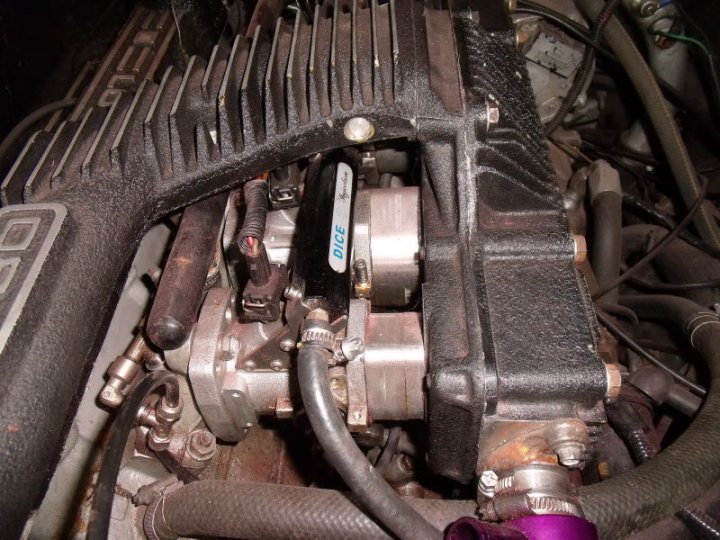 Greetings from a South African Esprit lover. - Page 1 - Esprit - PistonHeads - The image shows the engine of a car, with various metallic components, including belts, a pulley, and other mechanical parts. There is a purple hose connected to the system, which stands out due to its color. The image provides a close-up view of the engine, focusing on the intricate mechanisms and the components hooked up to each other. The exact make and model of the car cannot be identified from this angle and angle, but it is evident that this is the heart of the vehicle, the engine.