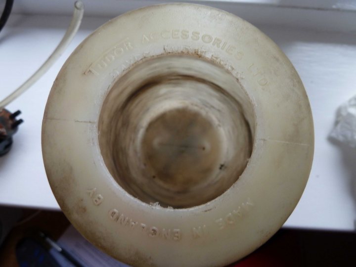 A close up of a cake on a plate - Pistonheads - The image features a vacuum cleaner hose with a tube attachment. The hose appears to be partially dirty and worn, with visible discoloration and debris. Attached to the hose's end is a tube with a rubberized, hexagonal opening, likely to be inserted into a vacuum cleaner. There is a label with a handwritten note on it. In the background, there's a blurred view of a power cord, which suggests that the setting is a workspace or a repair area.