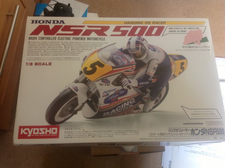 Your frivolous purchases, stuff you don't need... - Page 185 - The Lounge - PistonHeads - The image shows a sleek box for a model motorcycle named the Honda NSR500 Racing Motorcycle. The box prominently features the racing bib number 5, indicating it's likely a limited edition or special edition model. The background illustrates the racing environment, highlighting the excitement and speed associated with this model. The box is placed on a surface, possibly a desk or table, suggesting recent assembly or preparation for display.