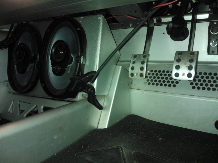 Pistonheads - This image shows the underside of the speaker setup in a vehicle, possibly an older model. The central focus is two black and silver speakers positioned towards the back of the vehicle. Each speaker is attached to what appears to be a metal frame, and the metal grating is in place to protect them. Wires are visible leading to these speakers, suggesting that they are connected to the radio or sound system. There is no text present in the image.