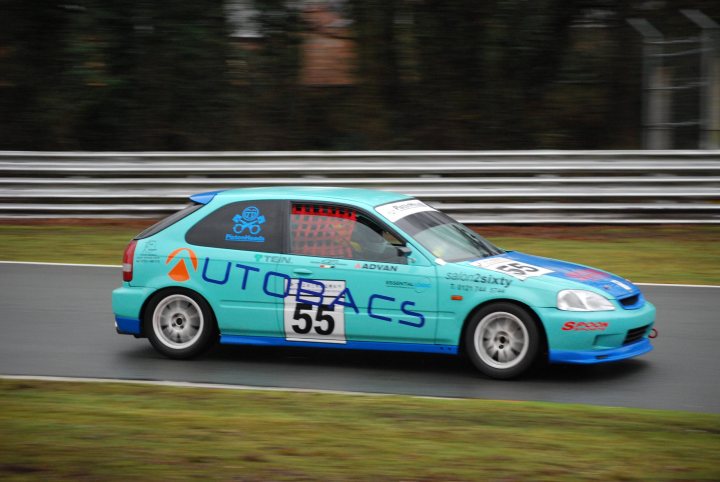 never see a ph sticker - Page 13 - General Gassing - PistonHeads - The image features a silver and teal track car, most likely a racing model, in motion. The car is decorated with various crests and designs related to Subaru, indicating it's a Subaru car. There are numbers on the side, indicating it could be used in racing events. The car is traveling on a track with a grass area alongside the runway, suggesting a controlled environment suitable for racing. The motion blur suggests the speed that the car is moving at, implying an exciting and competitive racing scene.