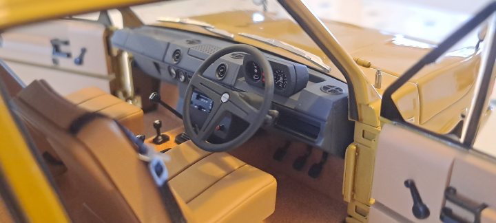 Pistonheads - The image shows a brown, four-wheeled vehicle that appears to be a remote control or toy car. It's positioned on a surface that is out of focus, which brings attention to the car itself. The interior of the car is visible, featuring a driver's seat with a steering wheel and other controls for various functions of the toy car. The exterior has a yellow color scheme, with no visible windows or doors. The backdrop is not detailed, ensuring that the viewer's focus remains on the vehicle. There are no texts present in the image.