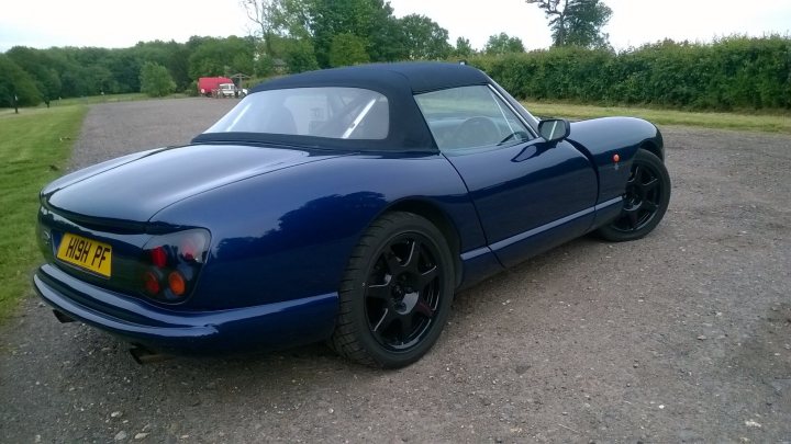 Random TVR pics - Page 414 - General TVR Stuff & Gossip - PistonHeads - The image features a striking blue open-top sports car parked on a patch of gravel near a grassy area. It has large, black spoked wheels that complement the car's sleek design. The license plate on the car proudly reads "W61 FY". The vehicle's position suggests it has just arrived or is preparing to leave. The setting appears to be a rural or semi-rural location, possibly a driveway or a rest area.