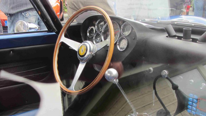 Hare Breakfast Meet - August - Page 1 - Kent & Essex - PistonHeads - The image showcases the front portion of a vintage vehicle featuring a steering wheel with wooden elements, typical of older automotive designs. The steering wheel is large, round, and features several small gauges. A metal gear shift knob is for steering, indicating the image might be capturing a moment of preparation for a drive. The gear shift level is not fully lifted from the dashboard, suggesting the car is parked or stationary. The steering wheel's wooden parts add a touch of elegance to the vintage feel of the car.