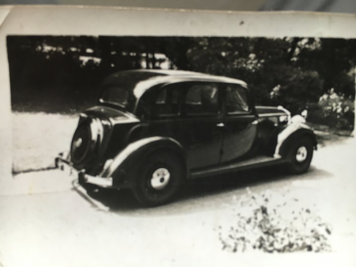 How about a 'period' classics pictures thread - Page 293 - Classic Cars and Yesterday's Heroes - PistonHeads - The image is a black and white photograph of a vintage car parked on a paved surface, likely in a driveway or on a side street. The car appears to be of a classic model, possibly from the mid-20th century, based on its design with curved fenders, a matching spare tire on the trunk, and the lack of prominent side mirrors. The background is indistinct but suggests an outdoor setting with trees, contributing to a conservative, perhaps older-generation aesthetic. There is no visible text on the image, and the focus is on the car, which is positioned centrally and occupies most of the frame. The tire detail on the car indicates the use of classic-style whitewall tires, which were popular in the past but have largely been replaced by radial tires in most modern vehicles.