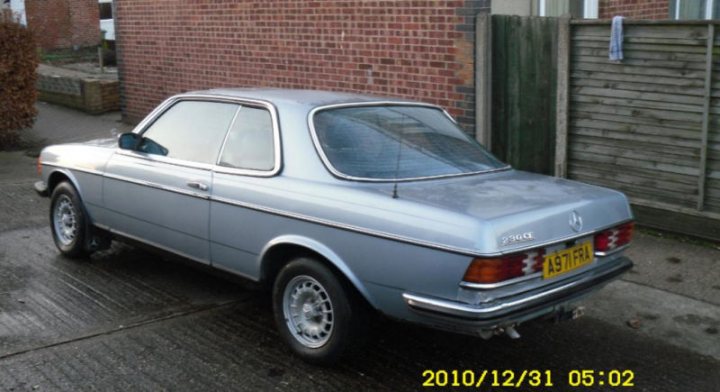 Pistonheads - This image features a small, silver Mercedes-Benz S-Class hatchback that is positioned at an angle parked on a concrete driveway. The vehicle is shown from the side and appears to be used, with some rust on the lower body and aged paint. Behind the car stands a brown brick wall, and to the right, there is a wooden fence with a blue towel hanging on the top horizontal rail. The car has a yellow license plate, and the photograph carries a timestamp in the upper right corner that suggests it was taken on December 31, 2010, at 6:02.