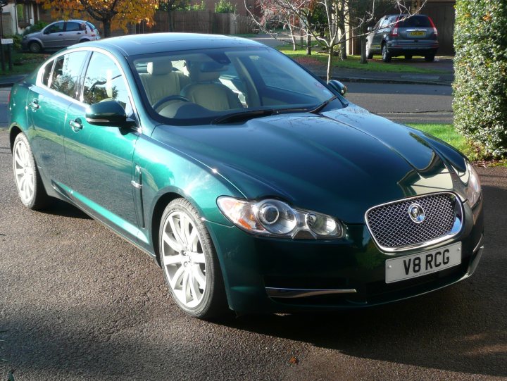 Get your Jags out - Show us your car - Page 12 - Jaguar - PistonHeads - The image shows a dark blue car positioned in a driveway. The car is parked alongside a road with trees and grass in the background. It appears to be an auburn Bentley, as indicated by the silhouette logo visible on the front grill. The car's design suggests a high-end, luxury vehicle, and it has a clean and shiny finish. There is no one around the car in the photo.