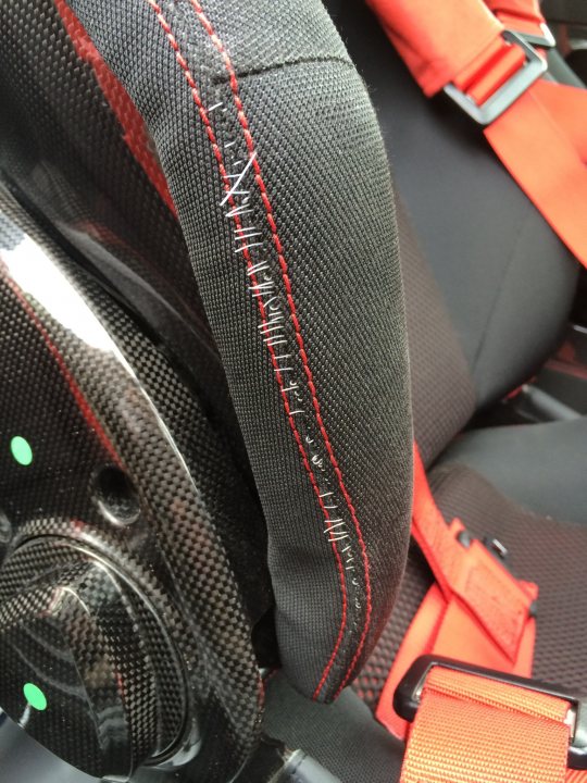 Frayed Seats on Scud - Bizarre? - Page 1 - Ferrari V8 - PistonHeads - The image shows a close-up view of the inside of a car seat, focusing on the headrest area. The headrest is noticeable for its red and black stitching with a black woven textile. The red stitching appears to be adding a decorative or functional material to the headrest. The stitching is clearly visible and adds a distinctive touch to the otherwise monochrome black car seat. There is a partial view of an occupant from the back, with the car seat cushion clearly visible. The design suggests a sporty or luxury style.