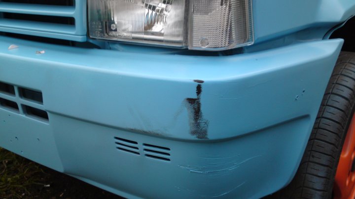 A blue truck parked in a parking lot - Pistonheads - The image features a close-up view of a single part of a blue vehicle. It appears to be an older model with a visible dent on the front bumper, which also has a large metal piece attached to its side. The paint is a faded blue color, indicating it may be older or more durable than standard vehicle paint. The headlight and signal lights suggest the vehicle is designed for road use, likely with a focus on utility or work vehicle applications.