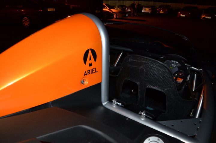 Essex Pistonheads March - The image shows a close-up view of the interior of a vehicle with a vibrant orange or Ariel brand part, labeled with the company's logo. This part is likely a part of the vehicle's hydrofoil system. The car's interior features several gauges and a steering wheel, typical of a driving setup. The photograph is taken in low light conditions, as indicated by the dark surroundings outside the vehicle and the need to use a flash or light source to illuminate the car's interior.