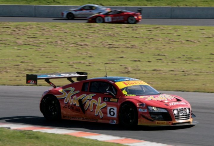 A red and white truck parked on the side of a road - Pistonheads - The image features a vibrant and dynamic scene from a racing event taking place on a circuit. The ground is covered with uniform grass, while the tarmac patches are clearly marked. The most prominent vehicle in the image is a racing car painted in a memorable combination of red, white, and yellow, featuring an eye-catching design with the word "SST" and the corresponding logo. The number "6" is prominently displayed on the side of the car. This high-performance machine appears to be one of several participants on the track, as evidenced by the blur of another similar car in the background, indicating movement and speed.