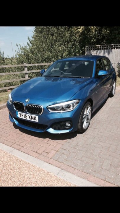 A car parked on the side of the road - Pistonheads - This image shows a modern, blue BMW car parked on a driveway. The vehicle is positioned at a slight angle, presenting a three-quarter view of its front end. It has a sleek design, with the car's headlights off, indicating that it is parked and not currently in use. The car's license plate reads "YF5 NK," and the setting appears to be a residential area, with a brick driveway and a wooden fence in the background. The sky above is partially obscured by clouds.