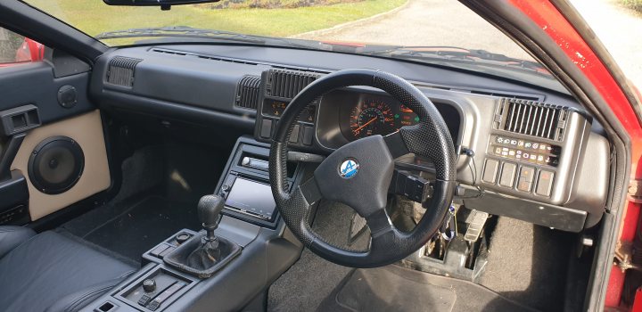 30 years old, some mega-mileage Renault erm... Alpine? - Page 4 - Readers' Cars - PistonHeads - The image shows an interior view of a car, predominantly in shades of red and grey. The car is filled with various pieces of equipment, including what appears to be a computer setup. There is a steering wheel on the left side, and a dashboard with multiple gauges and controls. A gearbox can be seen in the center, and the backseat has an array of buttons and levers. The car's roof and ceiling are open, revealing a network of wires and hoses. There is also an air conditioning unit mounted on the ceiling. The overall impression is one of a heavily modified or customized vehicle, possibly for scientific research or as part of an innovative project.