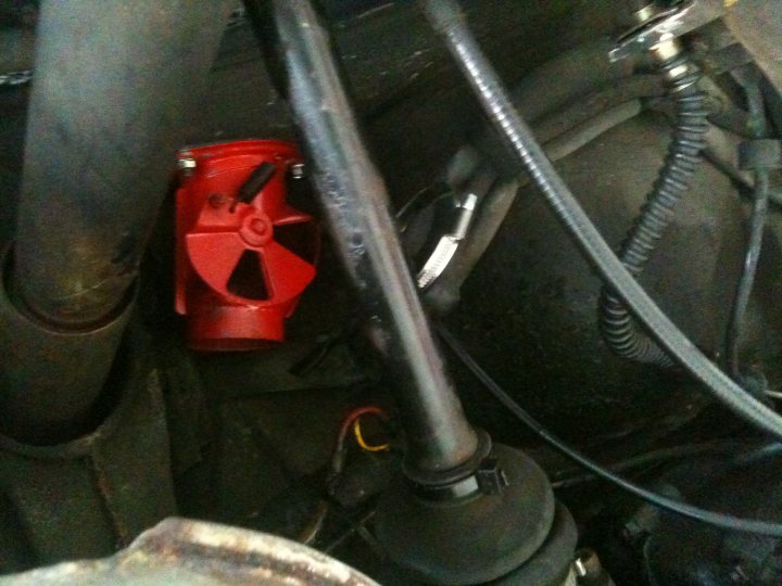 A close up of a black and silver motorcycle - Pistonheads - The image captures the mechanical heart of a vehicle - an engine bay strewn with various components and wires. Dominating the scene is a vibrant red muffler, its serrated edges hinting at a job well done in filtering out engine noise. Adjacent to the muffler, a wire coil, a defining element in electrical systems, weaves its path. The backdrop is a monochromatic symphony of gray and black pipes and wires, punctuated by the gleaming metal of a throttle valve. This is a snapshot of automotive engineering, where every component plays a vital role in ensuring the smooth operation of the vehicle.