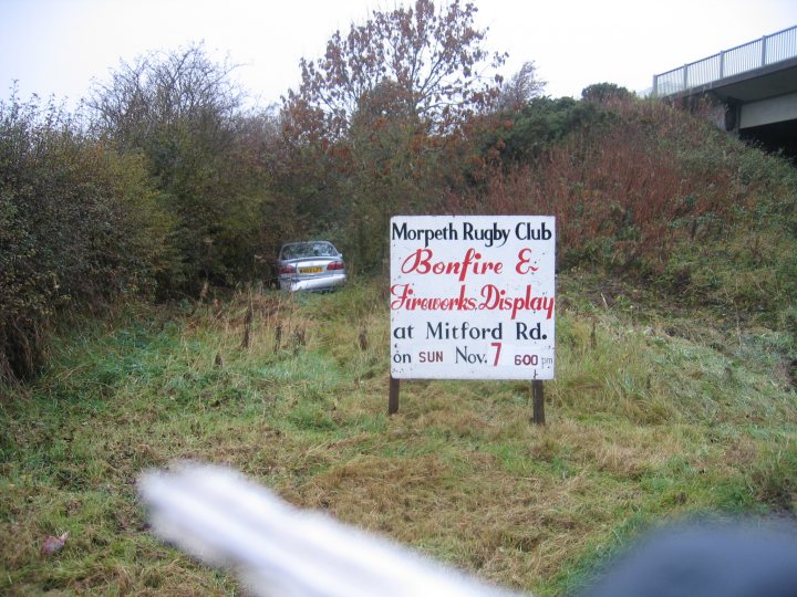 Be careful out there - Page 1 - North East - PistonHeads - The image showcases a rustic street sign for the "Morpeth Rampant Rugby Club." The sign advertises a local event, "Bonfire E Lovely Fireworks at Mildford Rd on Sun Nov 7th at 600." A person's hand with a thumb, possibly taking the picture, is visible on the bottom left, adding a human element to the scene. Behind the sign, a bit of the surrounding area is visible, providing context to the location of the sign.