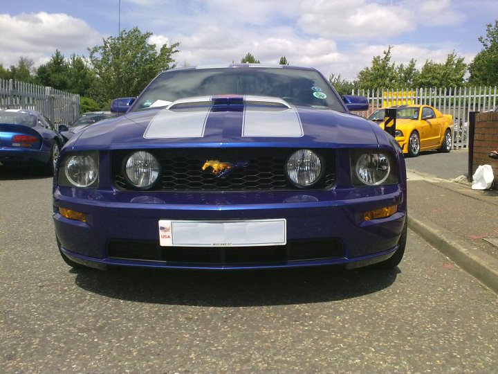 Atlantic Sat Sports Bbq Pistonheads July - This image captures a scene on a bustling street. The star of the show is a shiny **purple Mustang**, parked neatly on the side of the road. It's a luxurious model, complete with a yellow, Mazda logo, symbolizing its rebirth as a performance car. The backdrop of the scene includes a fence and a **yellow car**, adding a dash of color to the urban setting. The greenery in the background provides a contrasting element to the otherwise concrete and metal structures in the foreground.