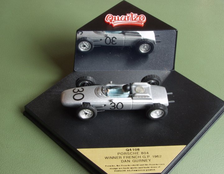 Pistonheads Collection - The image portrays a small, diecast model of a silver race car displayed on a green table surface. The car is set on a black platform against a green backdrop. Atop the platform is a black cardboard box with the number "30" prominently displayed, suggesting that this is a special edition or collectors' item.