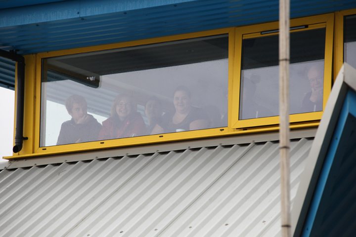 Pistonheads - The image captures a moment of leisure and camaraderie. A group of people, potentially a family or a group of friends, are enjoying a day out together. They are standing in front of a large yellow window, which is adorned with corrugated steel panels on the outside. The outside environment is a mix of blue hues, possibly indicating a clear sky, and some greenery. The window offers them a view of trees and the sky, enhancing their experience. The scene conveys a sense of connection and shared enjoyment.