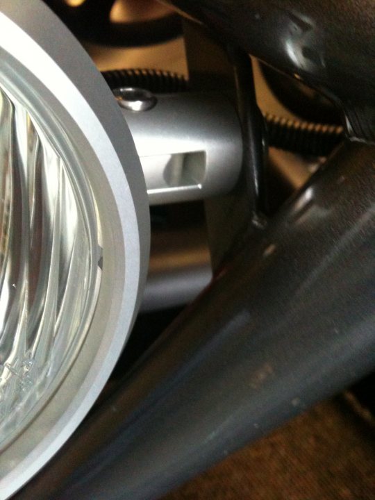 Led Atom Pistonheads Lights - The image shows a close-up of a silver motorcycle engine cover with a round, metallic emblem in the center. The emblem is shiny, reflecting the light in the room, which adds a sparkle to the surface. The surrounding motorcycle components, which appear to be shiny metal tubes and connectors, indicate that this is a part of a motorcycle's engine area. The perspective of the photo suggests it's taken in a garage or workshop setting, with a focus on the details and craftsmanship of the motorcycle engine.