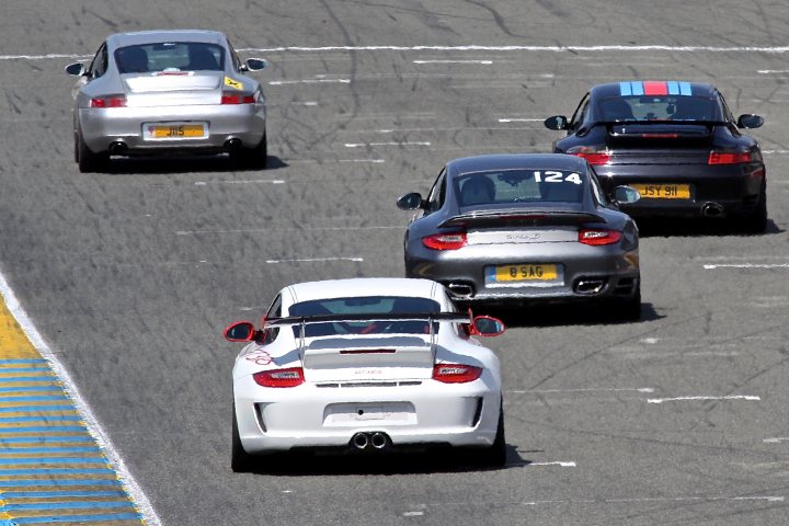 GT2 - Page 115 - Porsche General - PistonHeads - This image captures a dynamic scene of a car race on a track. There are four cars in the frame, each displaying a unique color and model. The cars are arranged in a diagonal line, creating a sense of motion and speed. Two of the cars are occupying the foreground, while the other two are positioned in the background, adding depth to the scene. The course appears to be well-maintained with clear lane markings. The image conveys the high-stakes nature of racing, where every second counts and the outcome is uncertain.