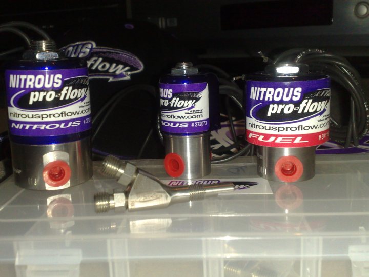 R5 drag car - Page 1 - Drag Racing - PistonHeads - This image shows three cans of nitrous fuel, which are typically used in racing or performance car enthusiasts. Nitrous oxide is a chemical compound that releases a burst of pressure when its container is punctured, hence the need for protective gear and safety precautions. The cans are lined up on a white surface, and a wrench is placed next to them, possibly for puncturing valves. The cans are labeled with the product name "Nitrous pro-flow", and one of them has an additional inscription "FUEL". The image captures the various elements involved in nitrous fuel handling, reflecting the thrill and risk associated with such automotive enhancements.