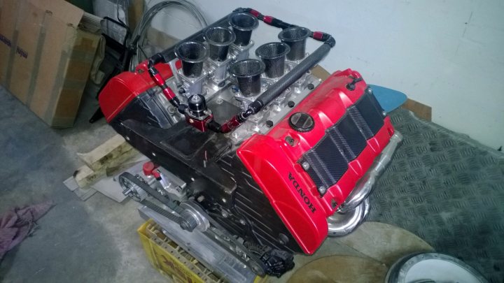 A motorcycle is parked on the side of the road - Pistonheads - The image showcases a large, red automobile engine with various parts attached to it, placed in what appears to be a garage or storage area. The engine is prominently featured in the foreground, taking up the majority of the frame. The surroundings include several boxes, pieces of wire or hose, and a hint of other mechanical parts. The setting seems to be a workshop or an area dedicated to automotive work. The overall style of the image is candid and informal, capturing a moment of activity within the space.