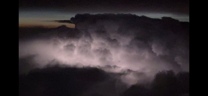 The image displays a dramatic night sky scene with clouds and lightning. In the lower right corner of the image, there is a rectangular border that looks like it might be from a video or photo editing software. This indicates that this image may have been taken during a stormy evening or captured as part of a timelapse or montage sequence, given the presence of multiple lightning strikes and the overcast clouds. The lighting in the sky is intense, suggesting either an actual storm or an artistic manipulation to create a dramatic effect. There are no texts or other objects in the image.