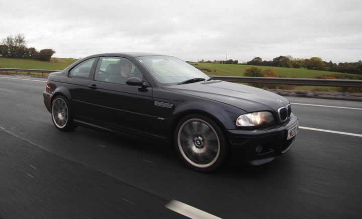 Pistonheads - The image shows a modern, dark-colored Bmw car traveling on a highway or road. The car has a clean design, with sleek lines and alloy wheels, indicative of luxury vehicles. The photo captures the side profile of the car, including part of the A-pillar and the front side of the vehicle's front wheel. The car is mid-motion, suggesting it is in mid-speed, and the roadmarkings are blurred due to the movement, creating a sense of speed. The sky is overcast, suggesting an overcast or possibly rainy day, and the surrounding environment is not fully visible, but it appears to be a wide, open road with no visible landmarks or signs.