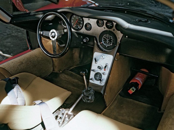 Fujima Alfa Romeo T33 stradale - picture heavy (possibly) - Page 1 - Scale Models - PistonHeads - The image showcases the cockpit of a vintage car prior to a start-up procedure. The steering wheel, with a stylish black center, is prominently positioned in front of the driver, suggesting a right-hand driving convention. An array of dashboard pods and gauges are located within easy reach, illustrating the trim design of the car. The gear shift, a pivotal control system, can be seen on the left side of the car, closer to the driver. A bottle of what appears to be champagne rests comfortably in the glove compartment, hinting at a celebratory or joyous occasion.