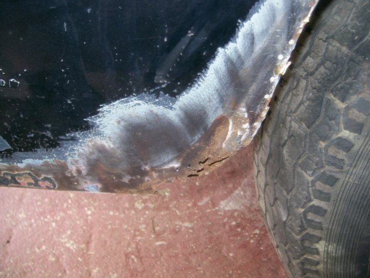 Pistonheads - The image captures a close-up view of a car's wheel arch, emphasizing the rust and corrosion that have ravaged it over time. The evidence of rust is particularly noticeable in the center of the metal components, where the dark orange and gray colors stand out starkly against the black of the rubber tire. The rear of the wheel, which is partially visible, appears to be protected from the elements, showing less signs of wear. The metal components are completely devoid of paint, adding to the rusty appearance. Despite the severe corrosion, the wheel and its supporting rubber seem to be in good condition, suggesting that otherwise, the car is mechanically sound.