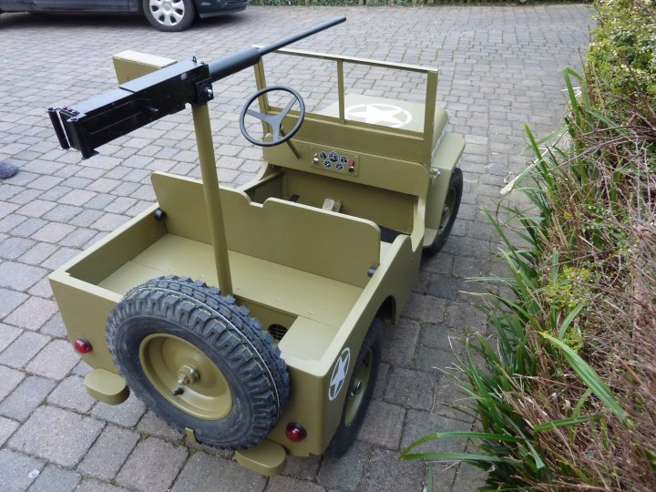 Toy Ultimate Pistonheads Boys - In the image, there's a vintage yellow cast iron toy truck with a large black wheel and a small black wheel. It appears to be a model of a World War II jeep. The toy truck is positioned on a brick driveway. In the background, there's a parked car. The truck is charmingly old-fashioned, adding a sense of nostalgia to the scene.