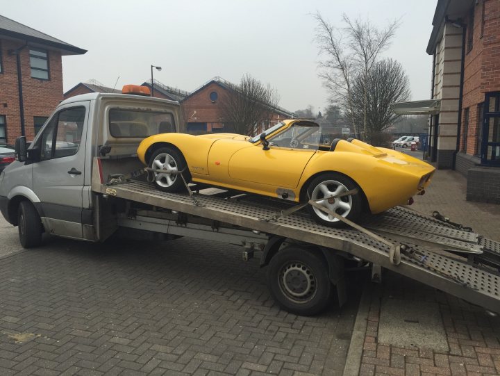 A red truck parked on the side of a road - Pistonheads - The image showcases a vibrant yellow sports car with white wheels being towed on a flatbed trailer by a grey van. The car, accompanied by a copper-colored trailer in a side view, seems to be embarking on an adventure through a suburban setting, as indicated by the brick buildings and leafless trees in the background.