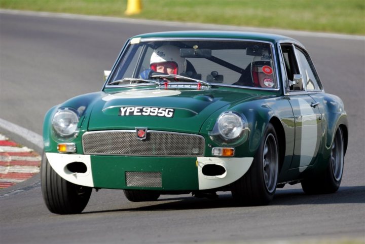 Body Mods Pistonheads - This image features a vintage racing car that is predominantly green in color. The car is in motion, as indicated by the blurred background, which suggests it is on a race track. The photo is taken in such a way that it captures the side profile of the car, with the wheels visible and the focus sharply on the vehicle. In the foreground, there is a yellow object, but it is not entirely clear what it is. The car has the text "YPE 990 SG" displayed on it, indicating a possible make and model.