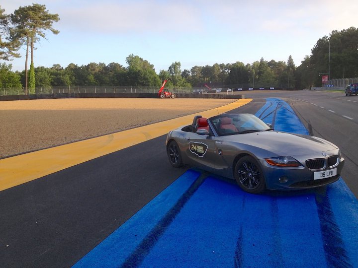 A motorcycle parked on the side of a road - Pistonheads - The image presents a glimpse of a unique motorsport experience. A silver BMW car is driving around a track painted blue, with a vibrant yellow curb providing a contrasting border. The setting is outdoors under a clear sky, with majestic trees lining the perimeter of the track. A truck is visible in the background, suggesting the setup for this event. The overall atmosphere suggests an exclusive and fascinating event, possibly a track day or a related promotional event.