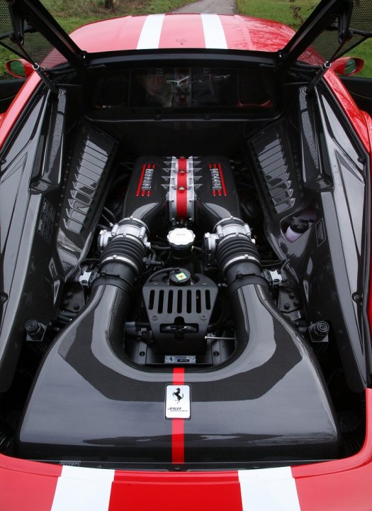 A close up of a motorcycle parked in a room - Pistonheads - The image showcases the powerful heart of a sports car, the Ferrari V12 engine. The engine is prominently displayed with an intricate black texture and silver accents, indicating the car's engine capacity of 12 cylinders. Red stitching adds a striking contrast against the black texture. The hood of the car is open, revealing the engine in its entirety, suggesting that it is either under inspection or being prepared for a drive. The engine bears the Ferrari logo, further cementing its identity as a high-performance sports car.