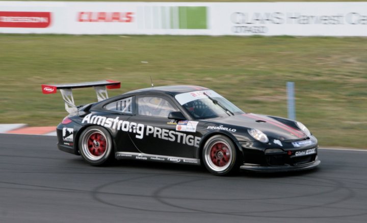 A car that is sitting in the street - Pistonheads - The image portrays an intense moment in a car racing competition. At the forefront of the image is a black Pirelli racing car, adorned with red and white stripes, and bearing the number 12. The car is captured in motion on a racetrack, leaning into a turn. Adjacent to the track are several vehicles, including a truck and a standard car, which serve as a stark contrast to the sleek and fast racing car. The background of the image features a advertisement for Bridgestone tires, indicating a sponsorship or partnership between the tire brand and the racing event.