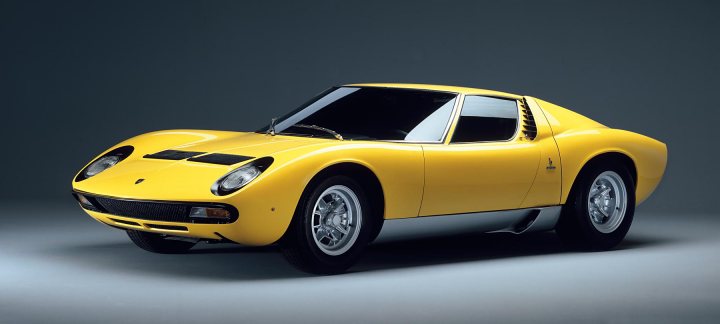 Your favourite car from the year you were born in... - Page 12 - General Gassing - PistonHeads - The image showcases a striking sports car painted in a vibrant shade of yellow. The car is positioned against a dark gray background, creating a strong contrast. It's a classic design, reminiscent of the 1960s, featuring a long hood and short rear, a layout often associated with racing and fast speeds. The interior of the car appears sparse, further emphasizing its focus on performance. The car is riding on classic alloy wheels, contributing to its sporty and timeless appeal.