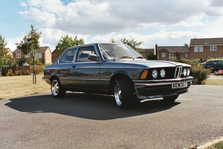 Year Birth Pistonheads - The image shows a royal blue BMW coupe parked on a paved street. The car is a model of an older generation BMW with distinctive twin-style headlights. Its license plate reads "AEM 852". The backdrop is a clear sky, suggesting a bright and sunny day, and there are residential houses in the background, indicating a suburban setting. The BMW is positioned in a way that the rear view and side window are visible.