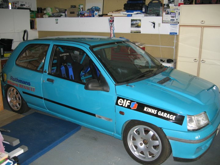 Cup Pistonheads Earlymid Clio - The image features a vibrant blue Volkswagen car parked indoors. The car is adorned with a black and red sticker on the back that reads "ELF KINNS GARAGE." The vehicle has a black roof rack and matching interior elements like seat belts and door handles. The photo captures the car from a side perspective, highlighting its distinctive blue hue and unique garage appeal.