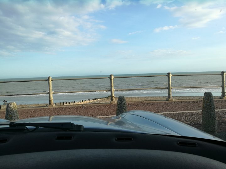 What did you do in the garage yesterday? - Page 232 - Chimaera - PistonHeads - This image captures a serene scene of a car parked next to a wooden fence overlooking the ocean. The perspective of the photo is from the driver's side of the car, with the steering wheel and part of the dashboard filling the left side of the frame. The fence, sturdy and tall, extends towards the calm water of the sea. The sky, painted with soft hues of blue and white, adds a touch of tranquility to the scene. Despite the car being stationary, there is a sense of anticipation and adventure, as if the car is ready to embark on a journey along the coastal road the ocean suggests beyond the fence.