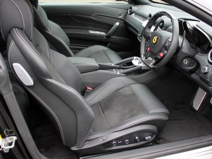 My First Ferrari - Page 1 - Ferrari V12 - PistonHeads - This image showcases the interior of a high-performance car. The front seats are deeply bolstered and upholstered in black leather, designed with a racing car influence. The front seat is equipped with a carbon fiber central console that houses the vehicle's controls, indicative of luxury and sporty elements. The dashboard and steering wheel are fitted with distinctive emblems and buttons, such as the yellow Ferrari logo, suggesting a high level of refinement and performance. The ambient lighting and the overall aesthetic of the car indicate a premium and tech-oriented vehicle.