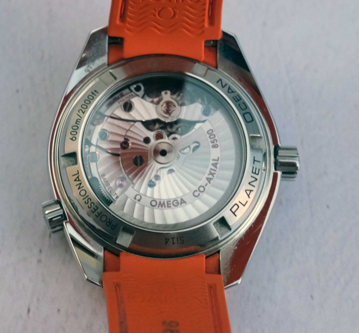 Pistonheads - The image features a wristwatch with an orange strap, prominently displayed on a white surface. The watch is a Swiss Omega Seamaster Planet Ocean, as indicated by the text and logo. It has a silver case and a red strap, giving it a sporty look. The dial of the watch is visible, showcasing various features such as a chronograph function, a date window, and possibly other subdials for additional functions. There is also an indicator or a small window on the side, likely for quick time reading or to adjust the watch. The watch appears to be in good condition, with no obvious signs of wear or damage.