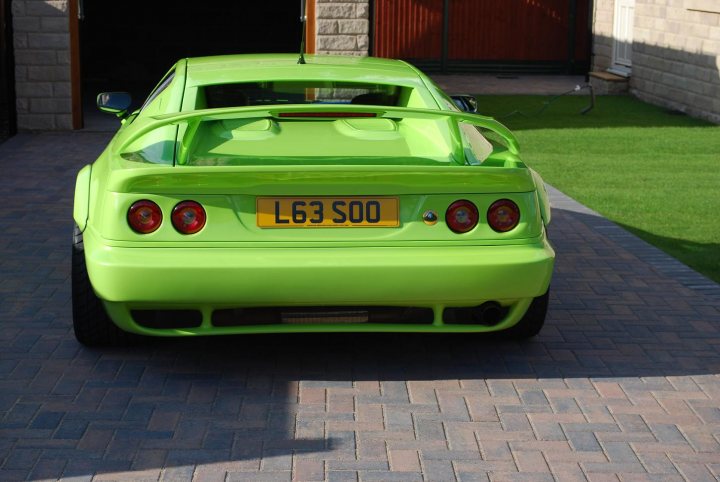 Pistonheads - The image features a bright green sports car parked on a brick driveway. The rear of the car displays a yellow license plate with black lettering, reading "L63 SO0". Above the license plate, the car's spoiler is visible. The vehicle is new-looking, possibly a custom or modified design, and there's a visible tag on the back indicating a number. The setting suggests a suburban domestic environment, possibly a residential driveway.