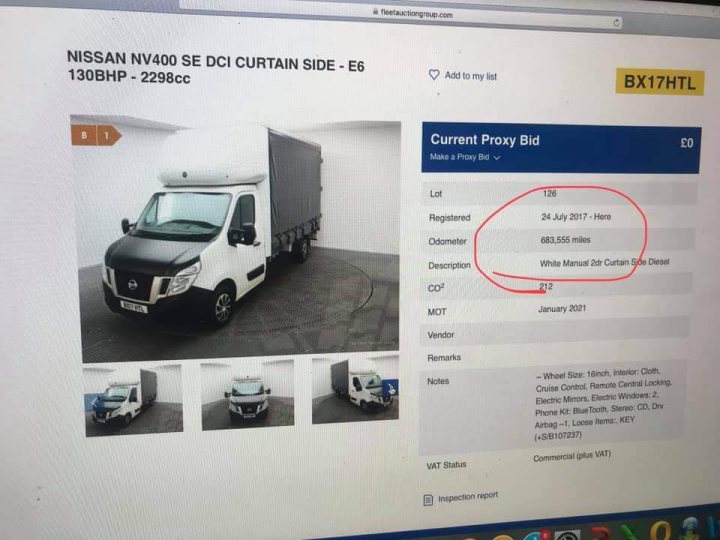 A white truck parked in front of a building - The image displays a screenshot of a webpage showing a vehicle listing. The vehicle is a black van or truck, parked inside what appears to be a covered area. The photo captures the driver's side window, with a slight glare on it. In front of the vehicle, there's a text box that seems to contain information about the car, although the exact details are not visible in this screenshot.