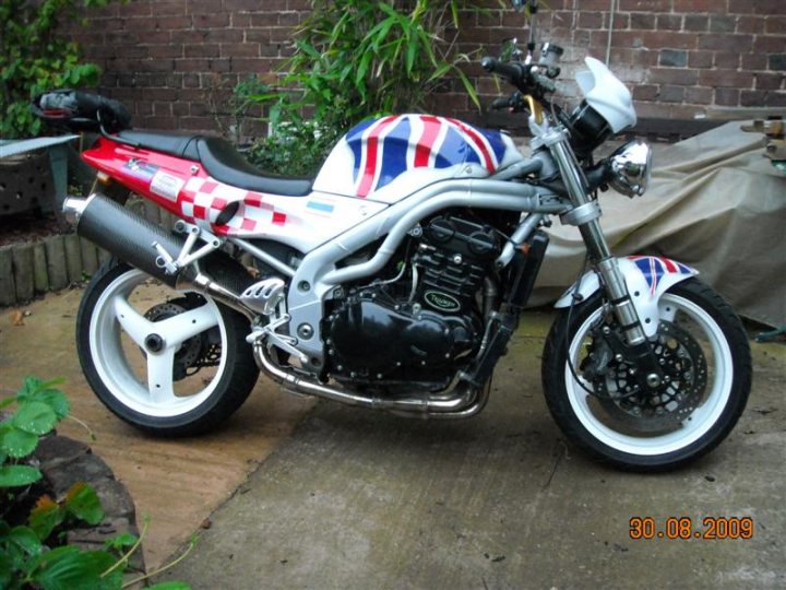 Any Bikers in here? - Page 1 - South West - PistonHeads - The image shows a flag-designed motorcycle parked on concrete pavement next to a brick wall. The motorcycle's exhaust pipe features a checkered pattern, and the seat is black. The British flag theme is prominent on the body of the motorcycle. There's a date and time stamp on the image.